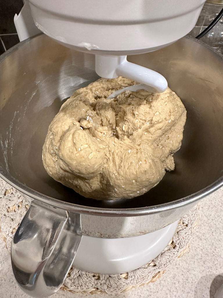 bread dough in bowl of stand mixer with dough hook.
