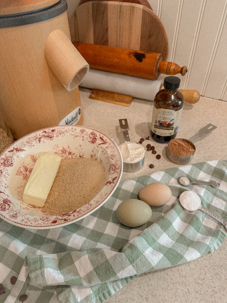 brownie ingredients measured and ready to add to pink and white bowl on counter with grain mill and green and white towel