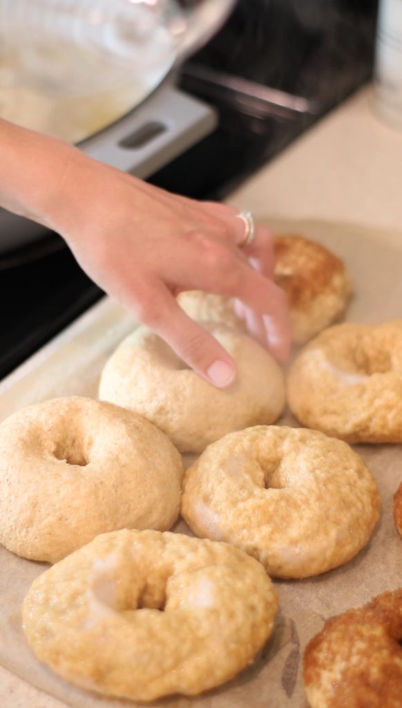 bagels on parchment paper beside stove before and after being boiled