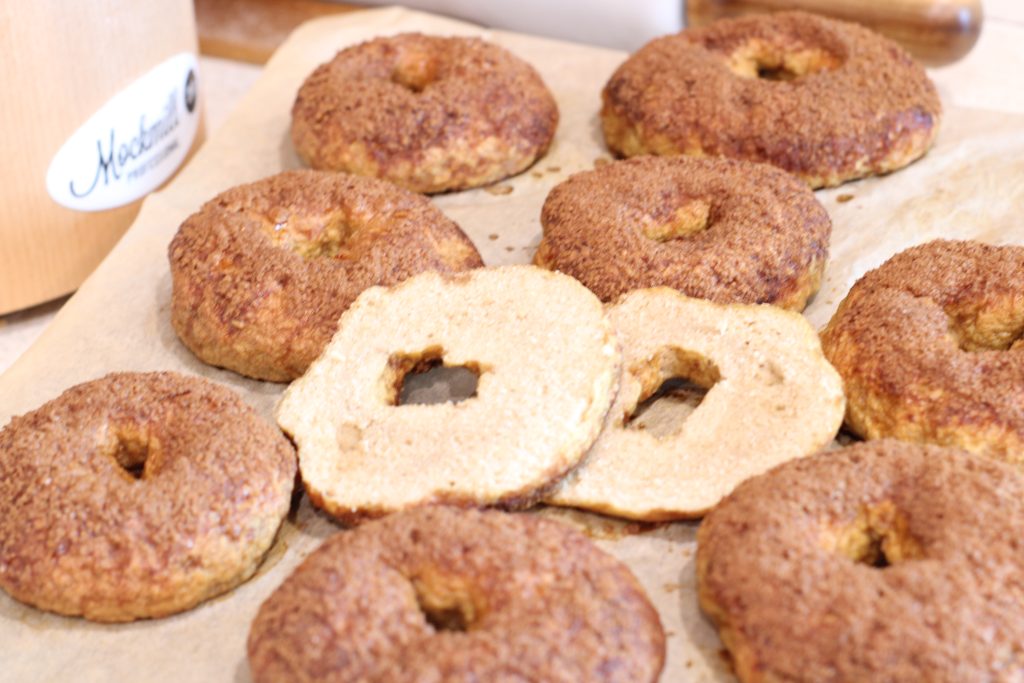 easy Homemade bagels with freshly milled flour after baking setting on parchment paper on counter beside grain mill
